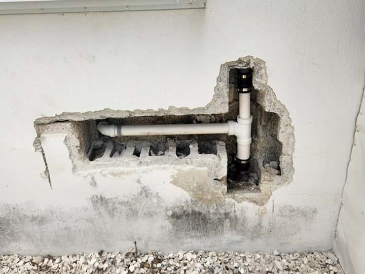 Water pipe leak repair requires cutting away concrete block wall.