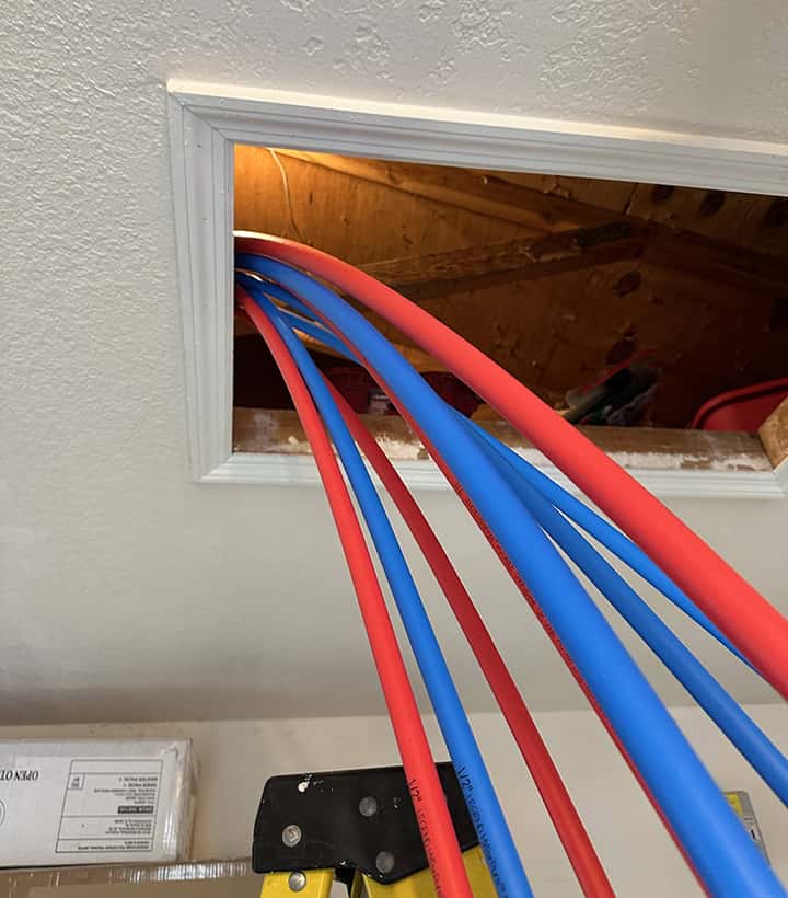 Installing hot (red) and cold (blue) pex pipes, running through attic access.